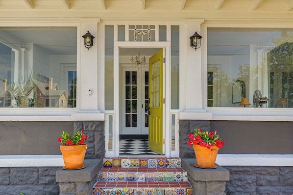 A house entrance with a checkered floor, a yellow door, and two potted plants. - Heart of Historic Dtwn Eustis! Mcm-inspired Home (Eustis)