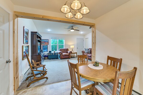 A dining area with a wooden table and chairs, a chandelier, and a ceiling fan.