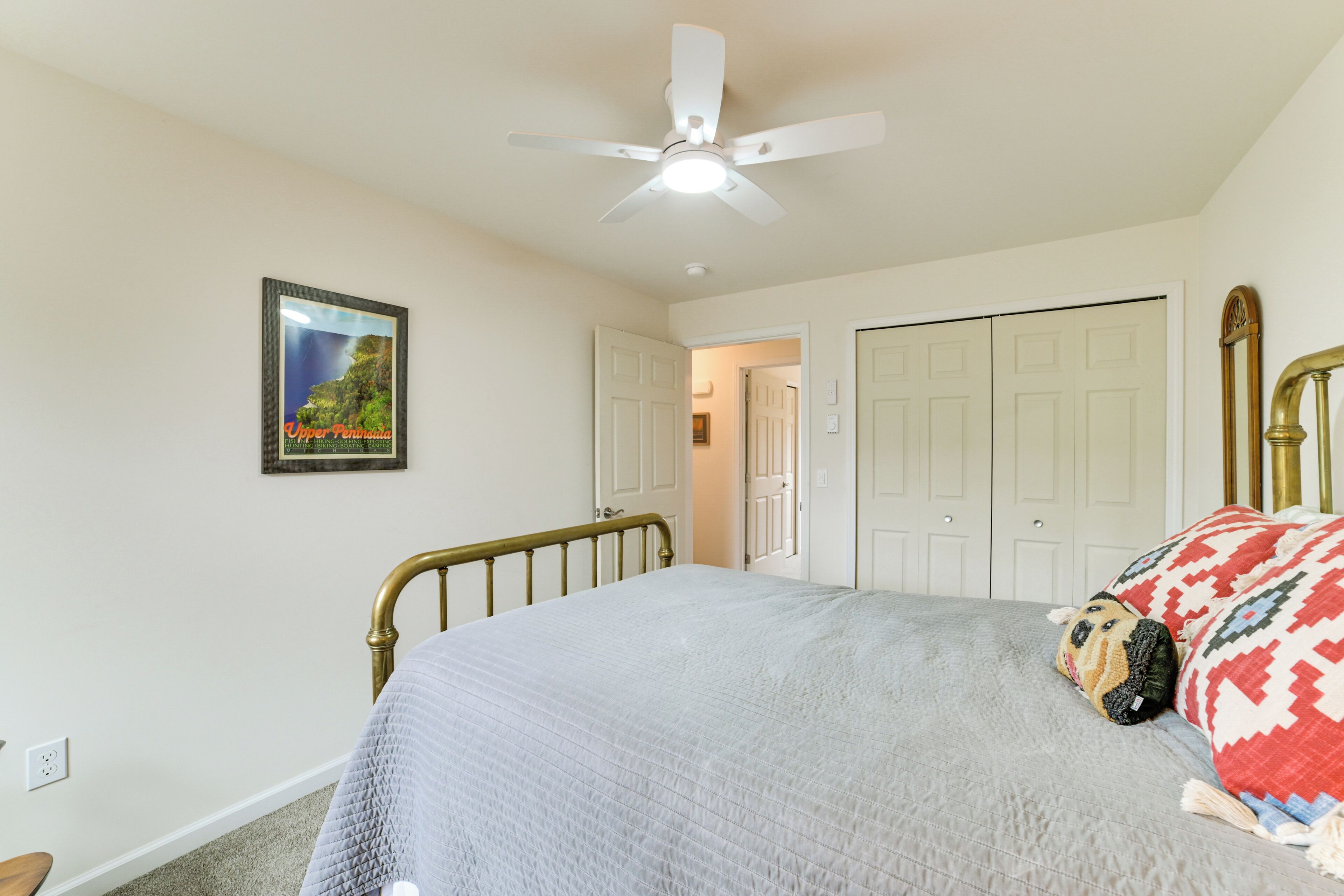 A bedroom with a bed, a ceiling fan, a framed picture, and a closet.