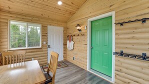 Un intérieur en bois avec une table à manger, des chaises, une porte verte et une fenêtre.