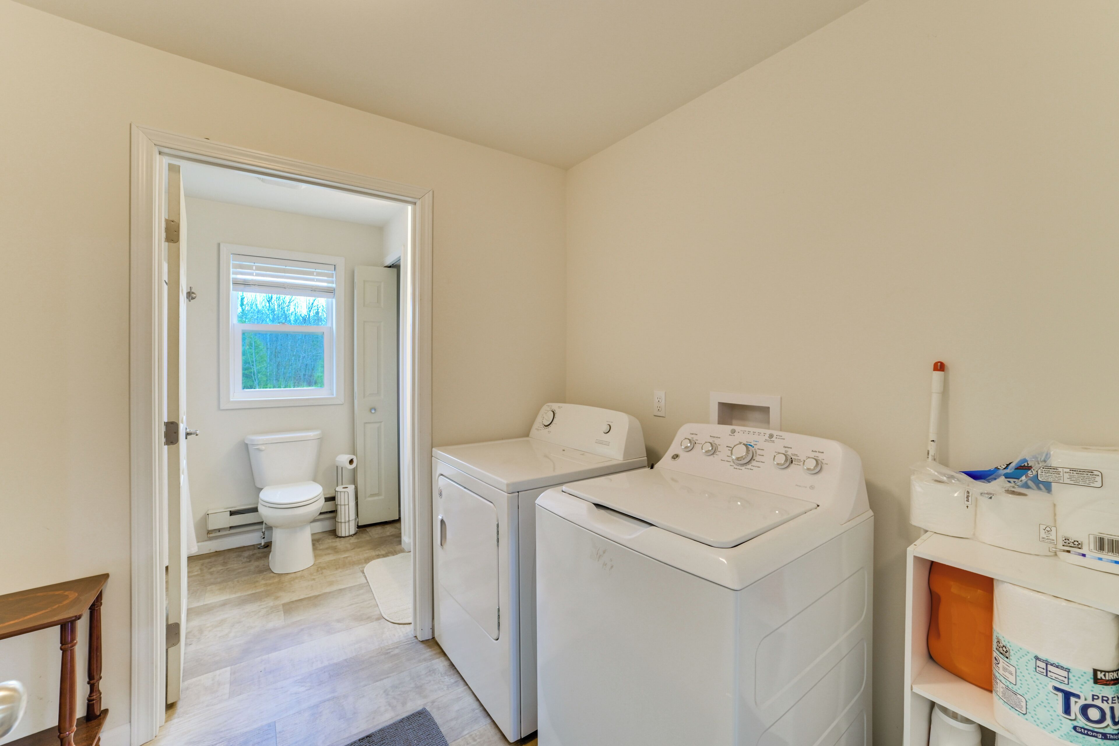 A laundry room with two washing machines, a dryer, and a toilet.