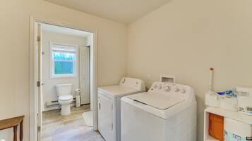 A laundry room with two washing machines, a dryer, and a toilet.