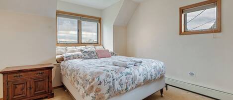 Een slaapkamer met een bed, een houten dressoir, een plafondventilator en een raam.