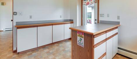 A kitchen with a wooden counter, white cabinets, and a tiled floor.