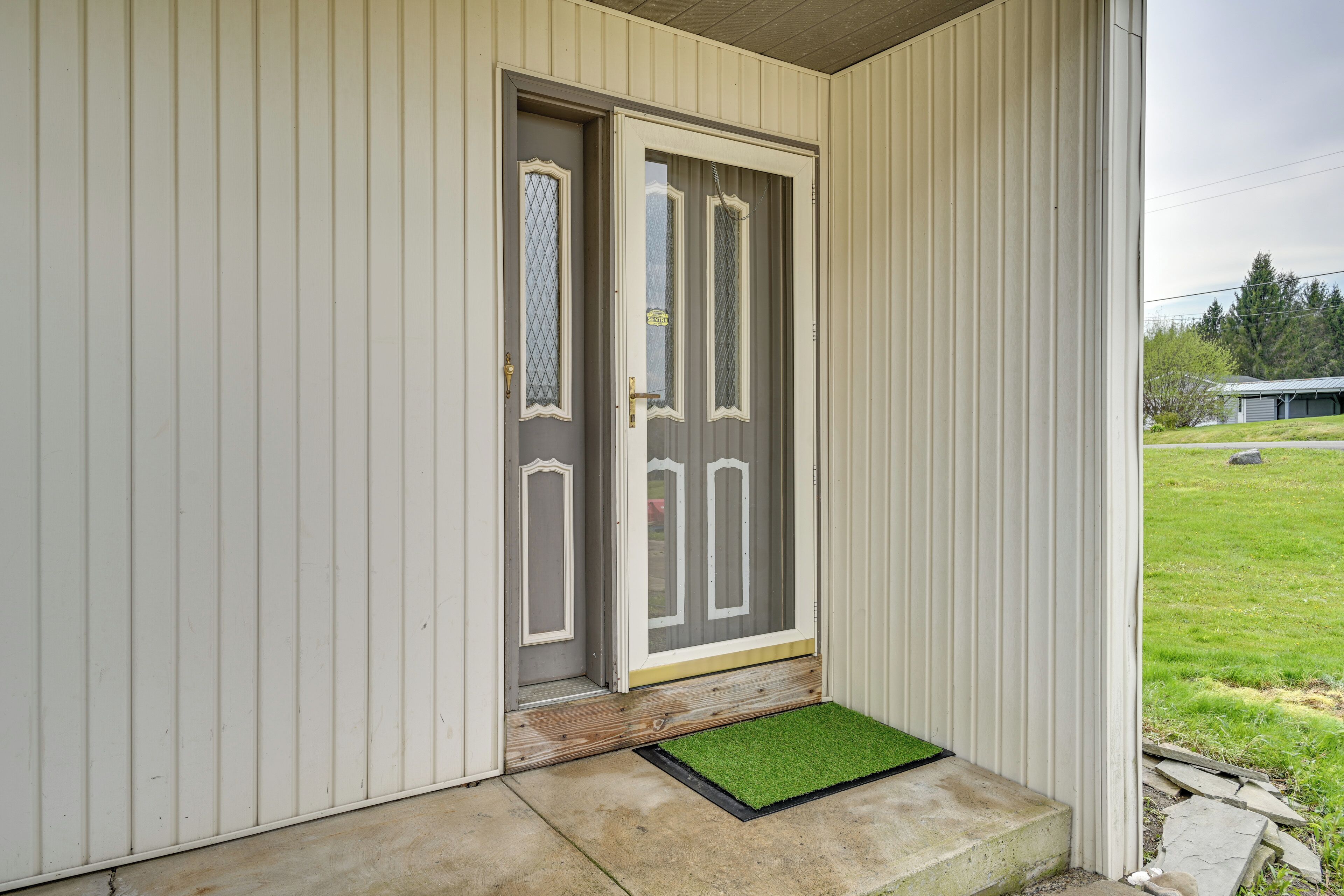 A house with a grey door, a small porch, and a green doormat.