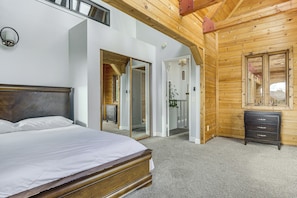 Un dormitorio con cabecera de madera, cama con ropa de cama blanca, cómoda y espejo.