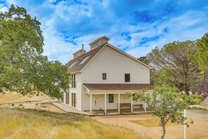 Une maison à deux étages avec un porche, une cheminée et une petite terrasse.