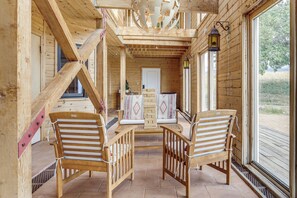 Una cabaña de madera con un balcón, dos sillas de madera, una mesa y vistas al exterior.