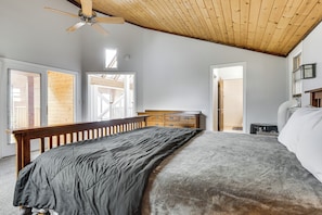 Un dormitorio con cama, cabecera de madera, ventilador de techo, cómoda y ventana.