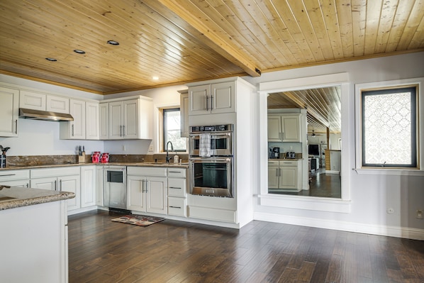 Una cocina moderna con armarios blancos, electrodomésticos de acero inoxidable y techo de madera.