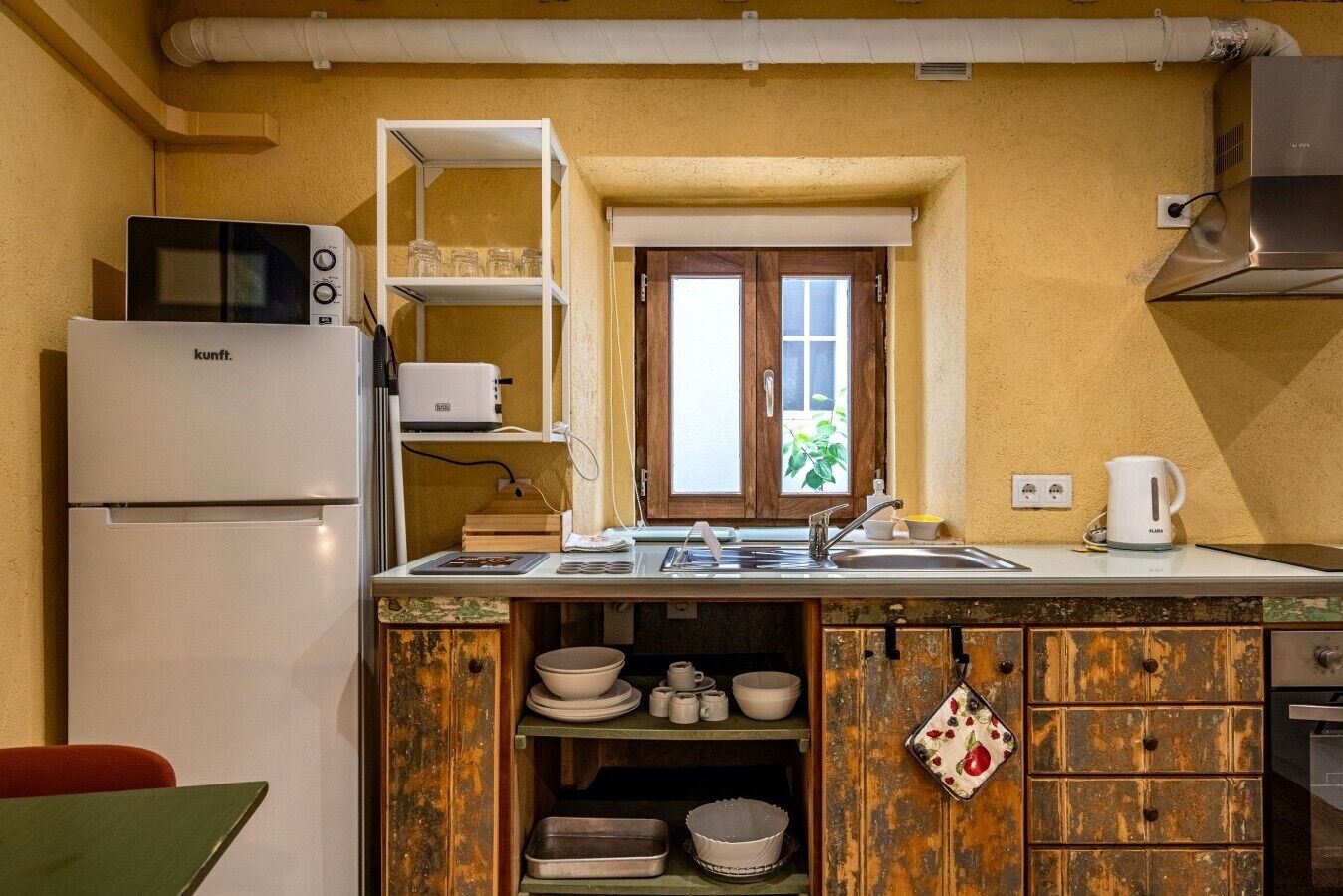 Una cocina compacta con microondas, un lavamanos y una ventana.