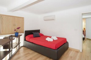 A bedroom with a bed, a desk, a wardrobe, and an air conditioning unit. - Captivating Loft in Prime Location Near Colosseum (Rome)