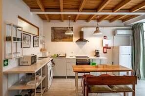 A compact kitchen with wooden beams, a dining table, and a bench. - Secret Riverside Studio in Porto Brandão (Caparica)