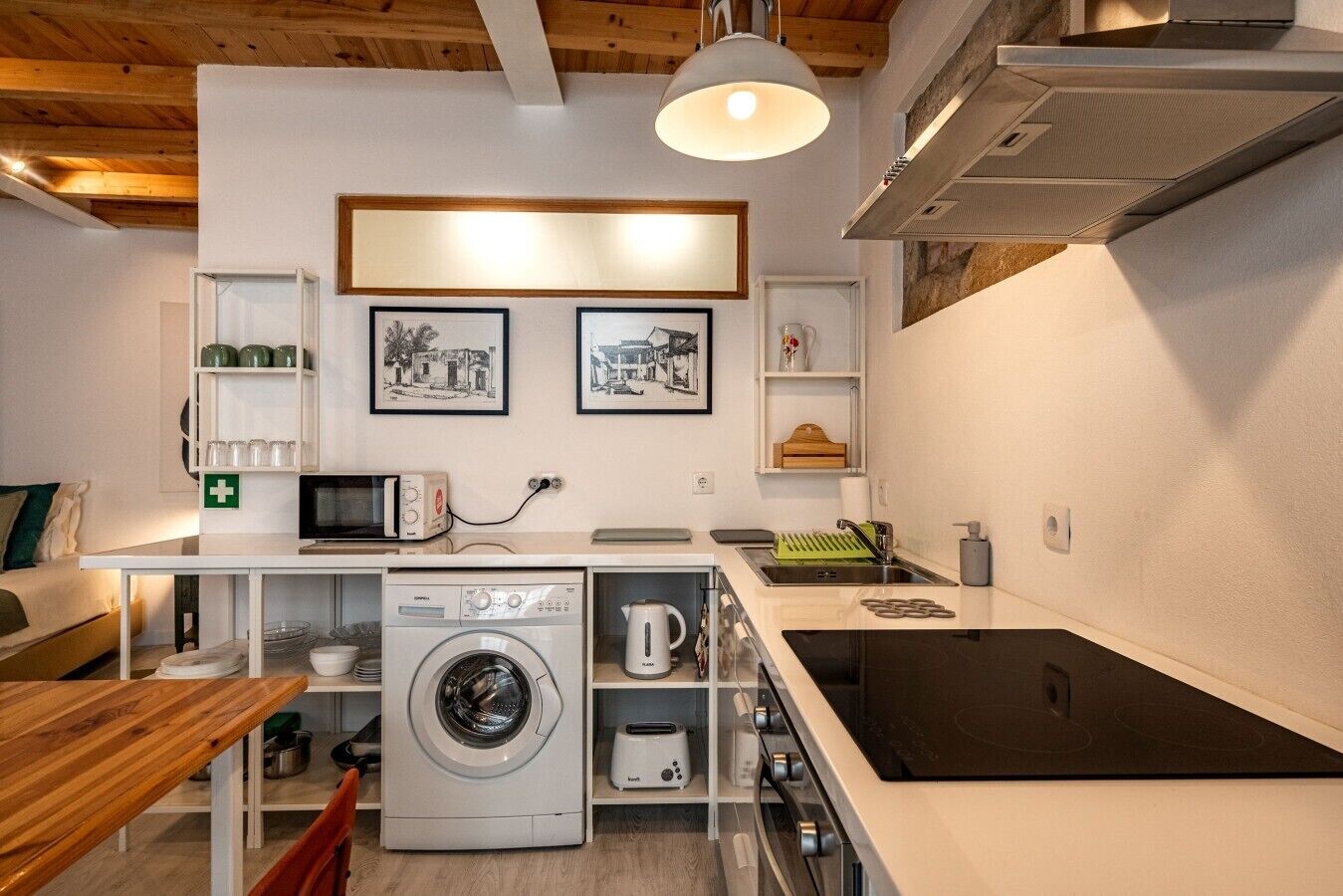 Cocina compacta con lavadora, microondas y lavabo.