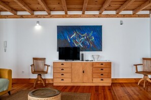 Ein Wohnzimmer mit Holzboden, einem großen abstrakten Gemälde, einem Fernseher und einer Holzkassette.
