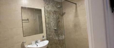 A modern bathroom with a glass-enclosed shower, a white sink, and a toilet.