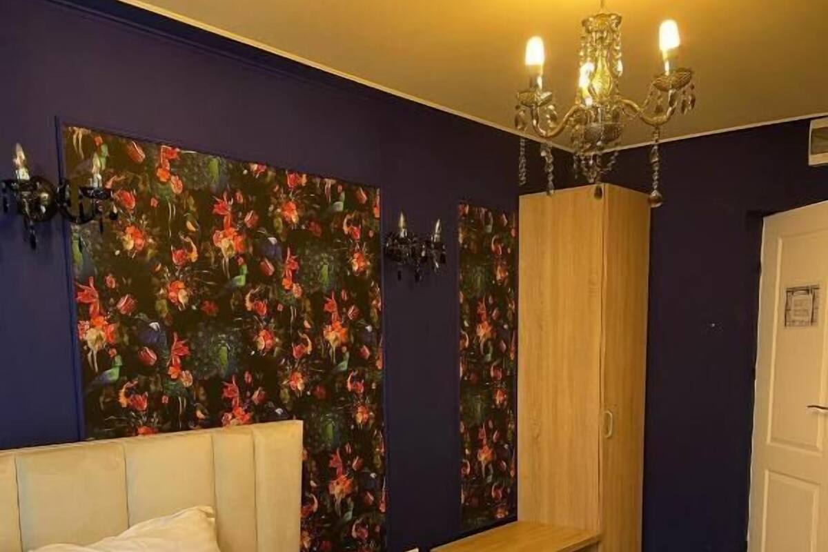 Ein Hotelzimmer mit Bett, einer Bank, einem Kleiderschrank und einer Kandelaber.