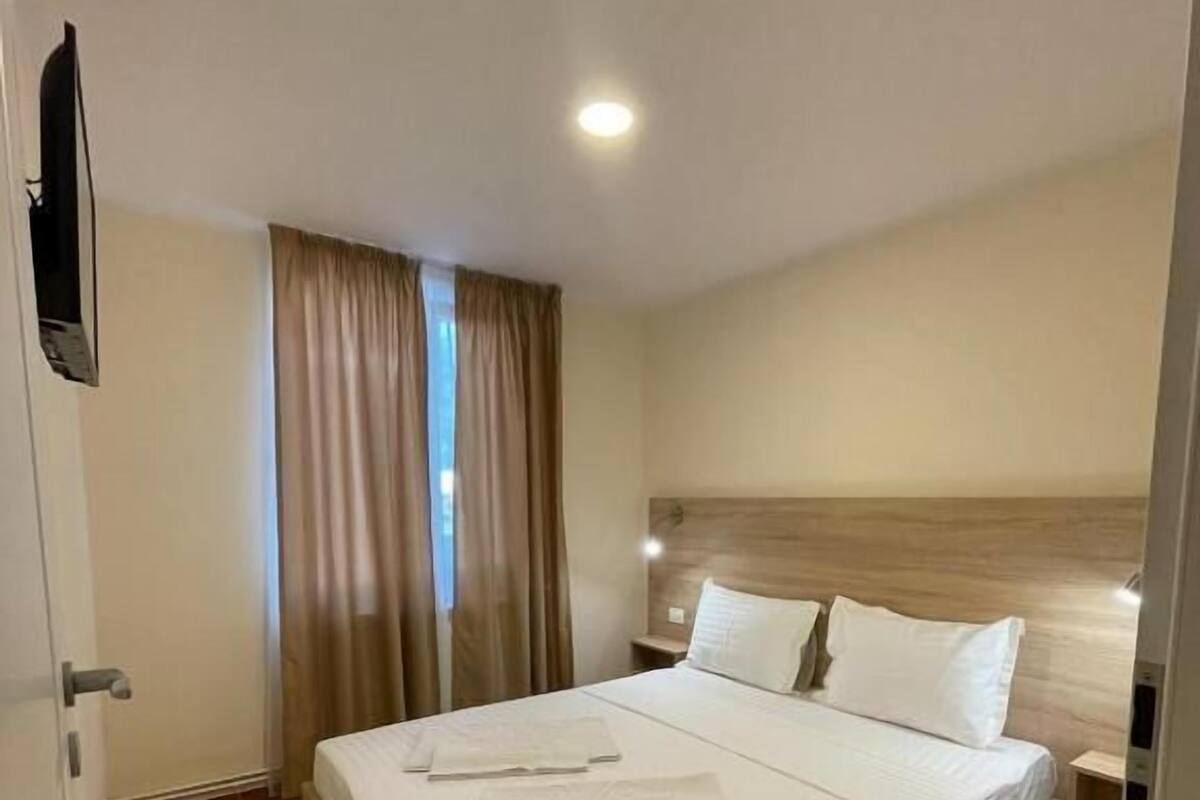 Ein Hotelzimmer mit einem großen Bett, einem Holzkopfteil und einem an der Wand befestigten Flachbildfernseher.