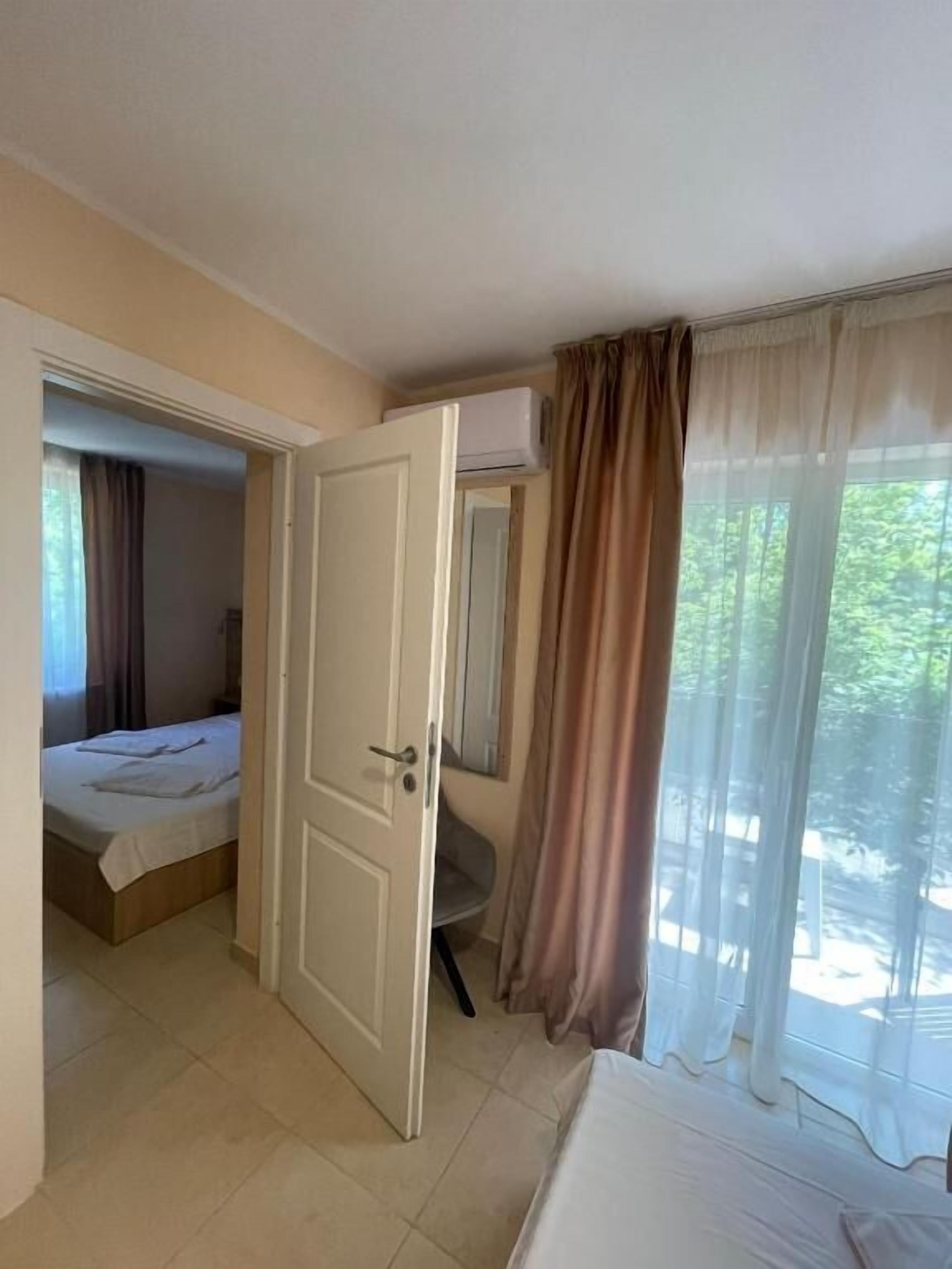 A hotel room with a bed, a desk, and a window with curtains.
