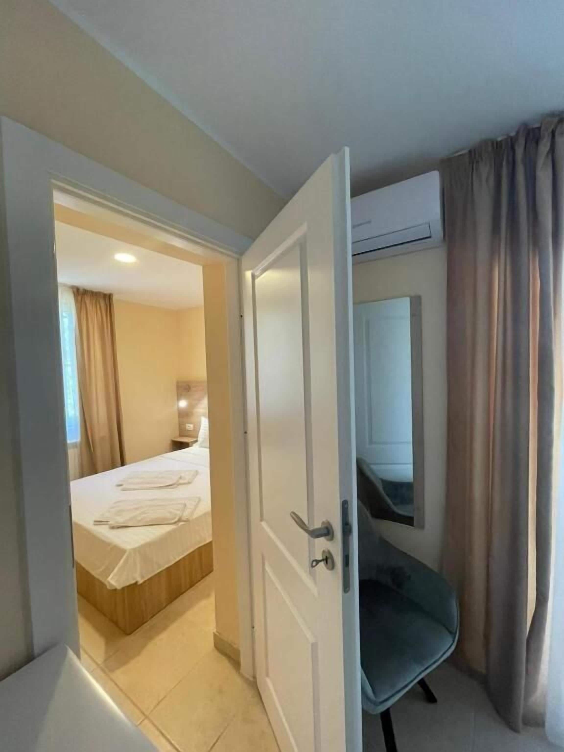 An open door leading to a bedroom with a bed, a chair, and a mirror.