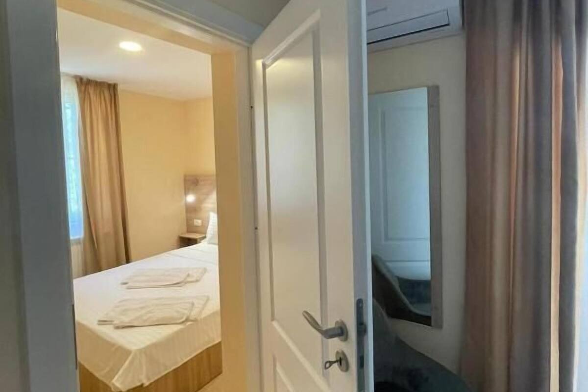 Eine offene Tür, die in ein Schlafzimmer mit einem Bett, einem Sessel und einem Spiegel führt.