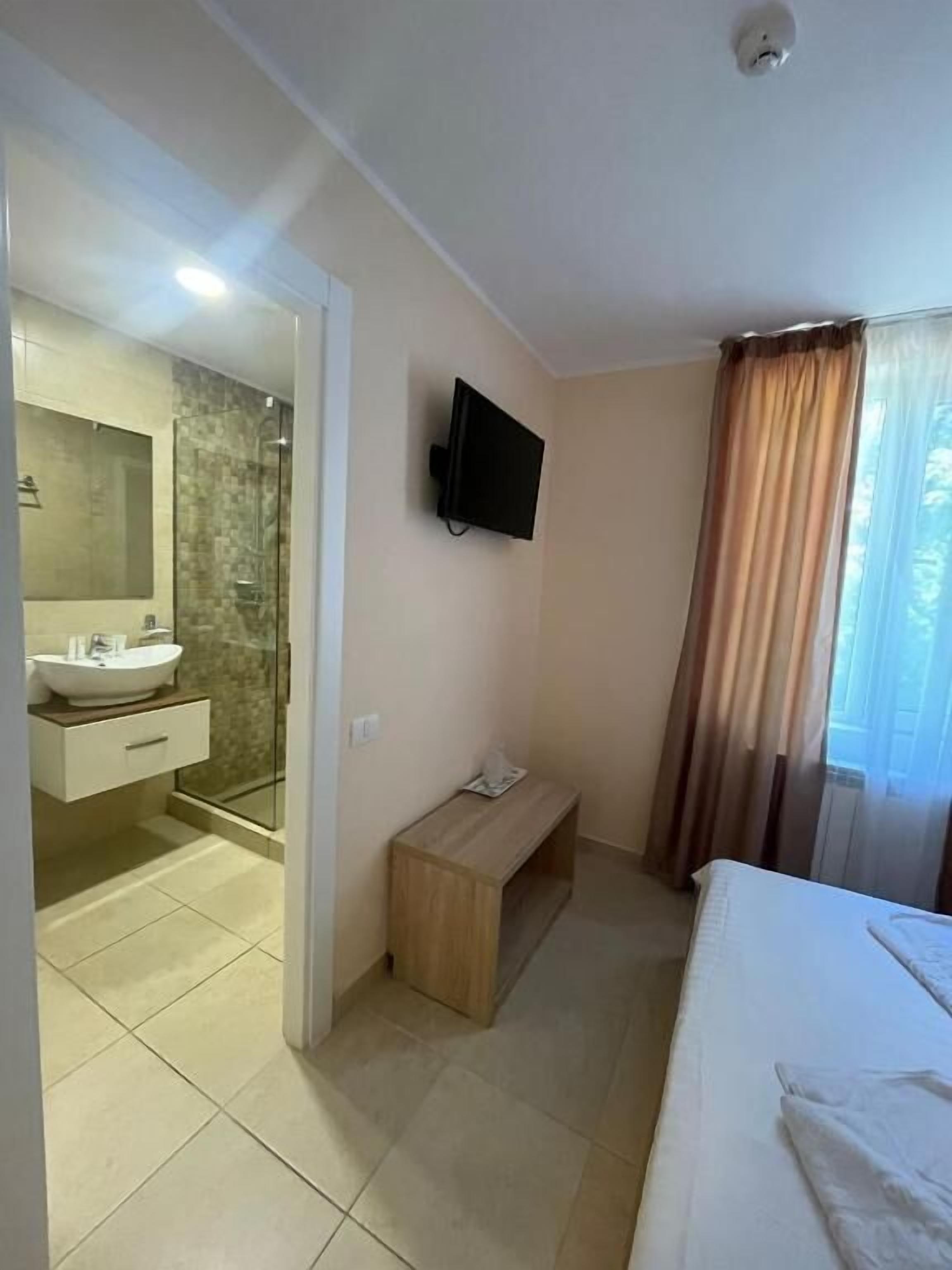 Ein Hotelzimmer mit Bad, Fernseher, einer Bank und einem Bett.