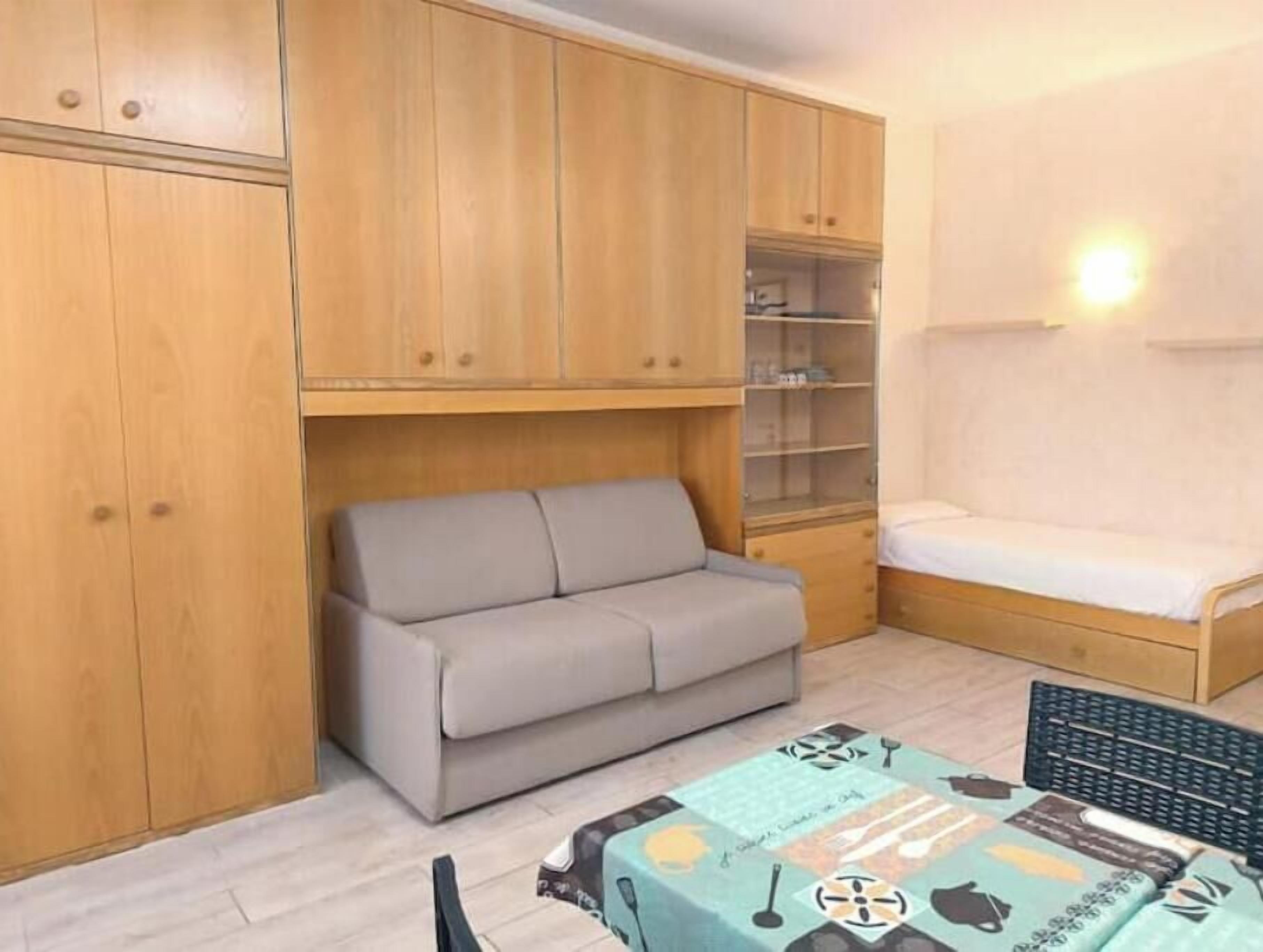 Une petite pièce comprenant un canapé, un lit, un bureau et des armoires en bois.