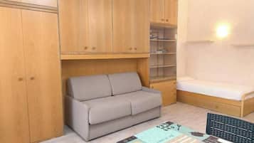 Une petite pièce comprenant un canapé, un lit, un bureau et des armoires en bois.
