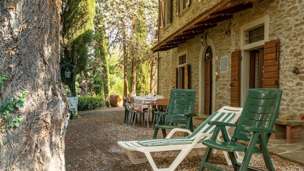 A stone building with a gravel patio, outdoor seating, and a tree. - Holiday Home 'Il Granaio' with Shared Garden and Wi-Fi (Arezzo)