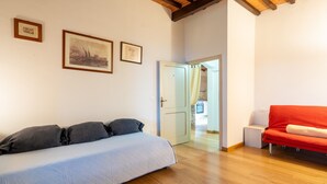Une chambre à coucher avec un lit, un canapé rouge, un plancher en bois et des tableaux encadrés accrochés au mur.