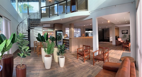 A spacious hotel lobby with a staircase, seating areas, and a reception desk.. Ipê Hotel Jardins