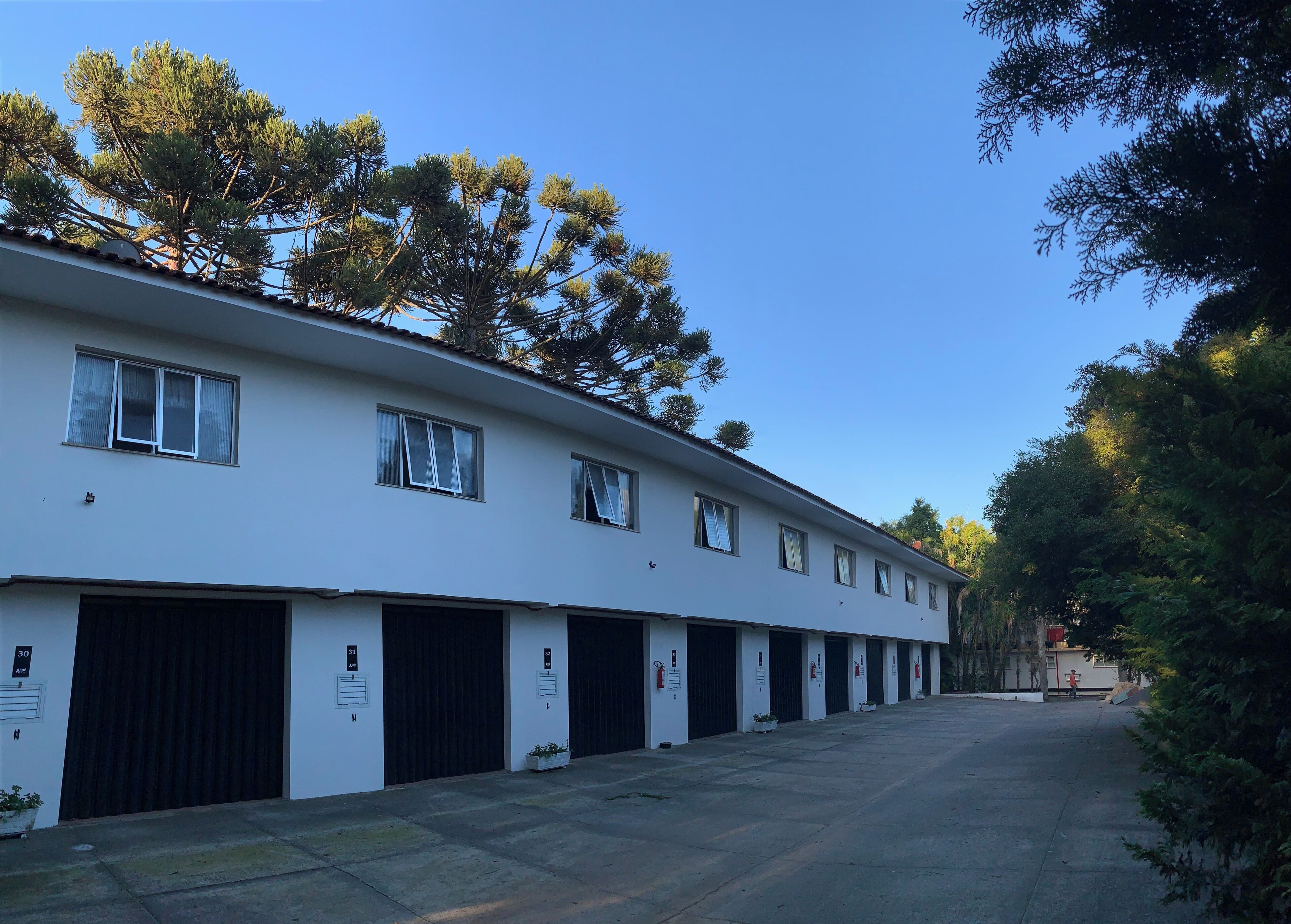 Un edificio con varias puertas tipo garaje, techo plano y cielo despejado.