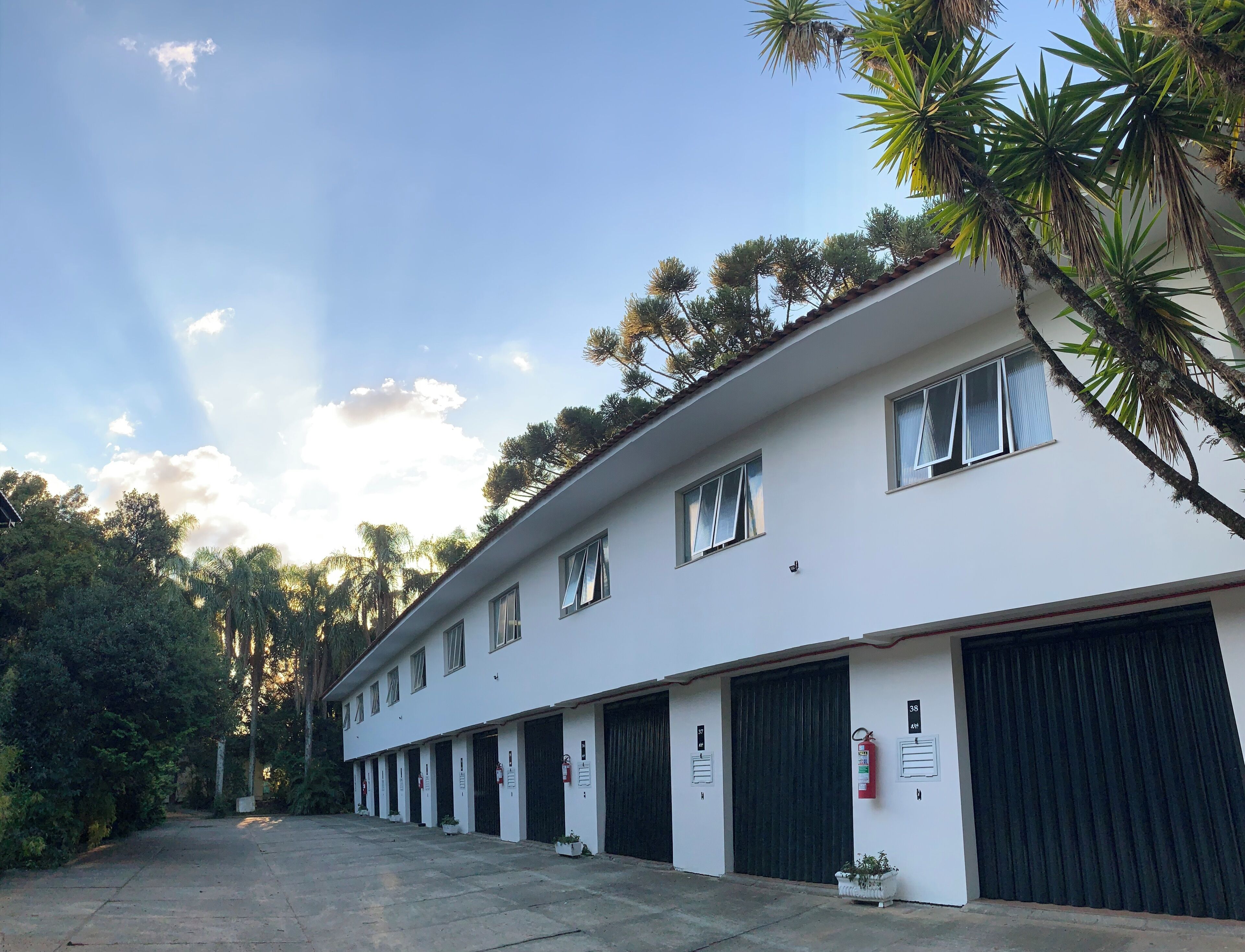 Um edifício branco com várias garagens, uma fileira de janelas e um céu limpo.