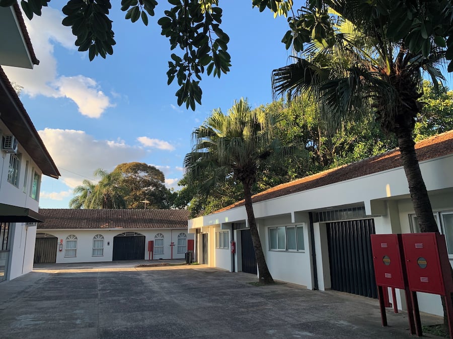Pátio com um edifício, palmeiras e céu claro.