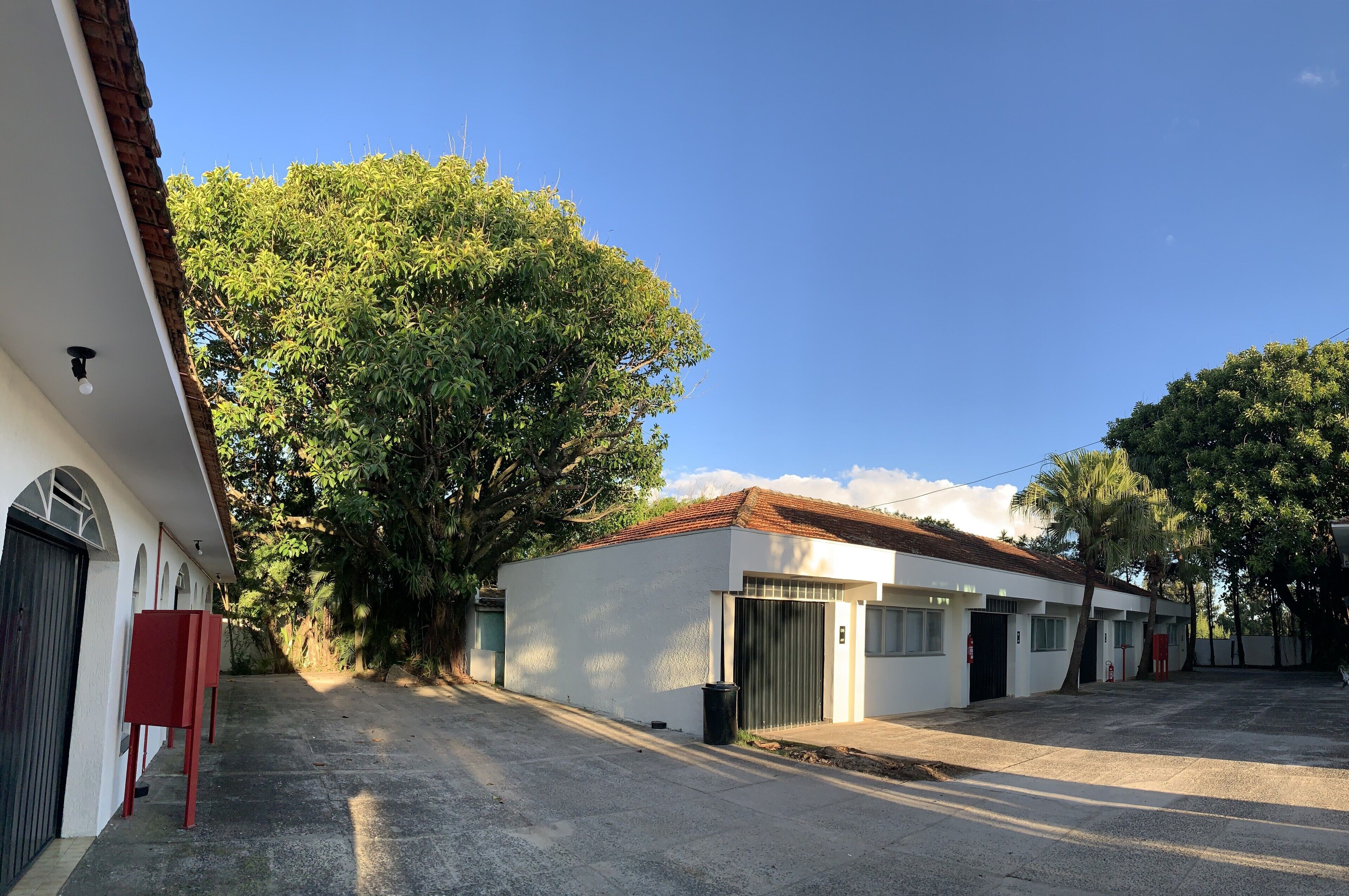 Un edificio con fachada blanca, puerta roja y puerta de garaje.