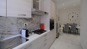 A modern kitchen with white cabinets, a gas stove, and a built-in oven. - Seaside Apartment - Sleeps 6 - Balcony (Rapallo)
