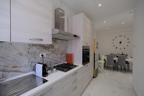 Eine moderne Küche mit weißen Schränken, einem Gasherd und einem eingebauten Backofen.