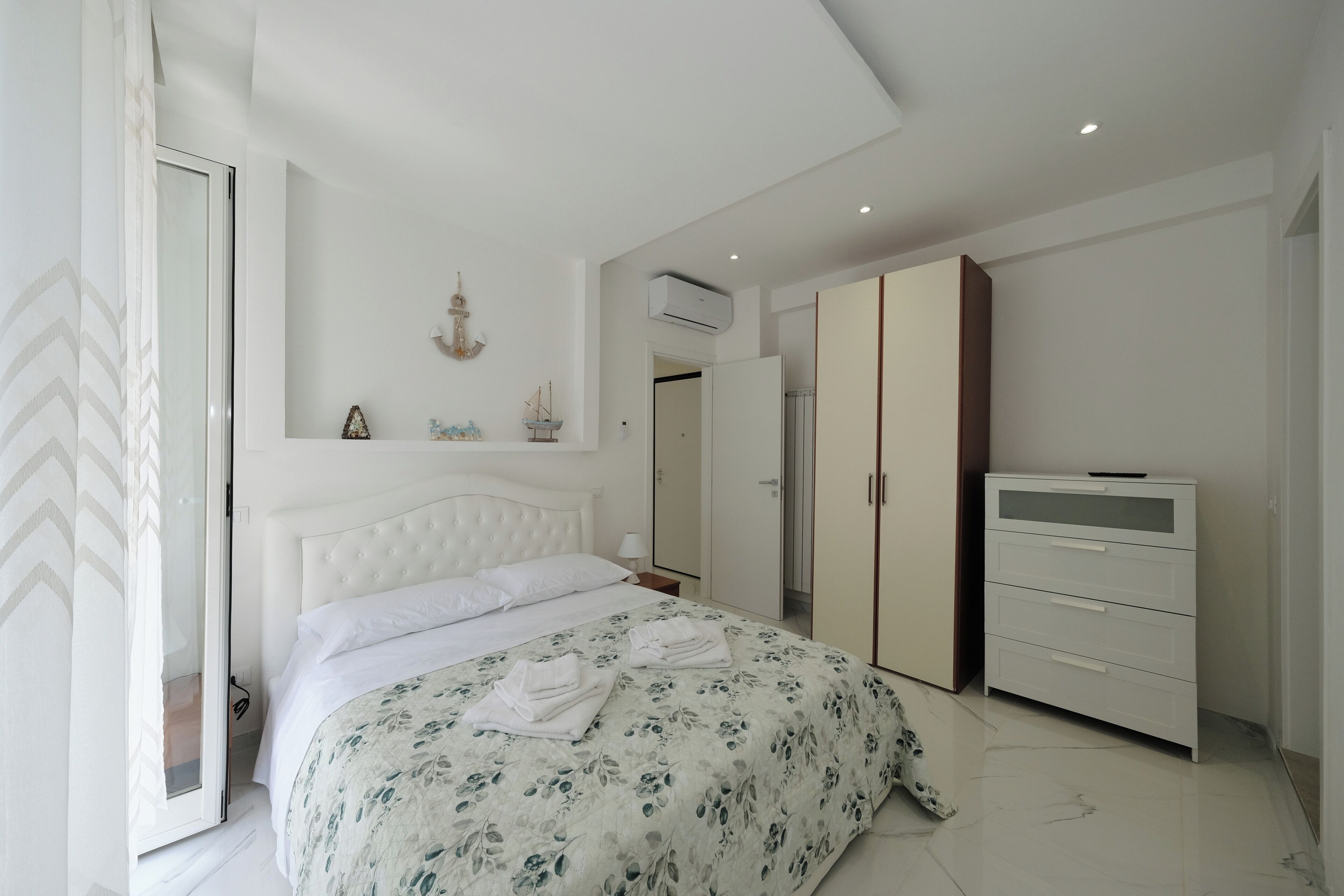 Un dormitorio con cama, armario y una estantería para televisión.