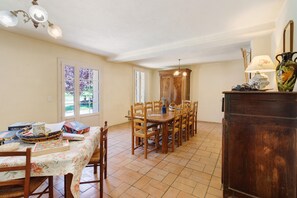 Ein Essbereich mit Holztisch und Stühlen, einer Kristallleuchtre und einem Schrank mit einer Vase.