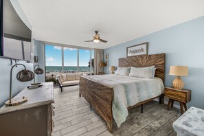 Ein Schlafzimmer mit einem Bett, Nachttischen, einem Schreibtisch und Meerblick.