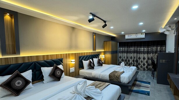 A hotel room with two beds, a desk, a chair, and a large window with curtains. - Yatri Stay inn (Mumbai)