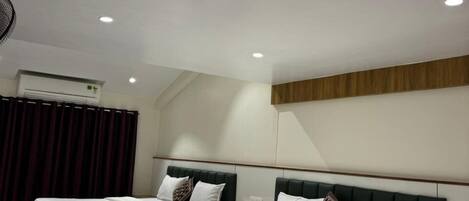A hotel room with two beds, a ceiling fan, an air conditioning unit, and a wooden headboard.