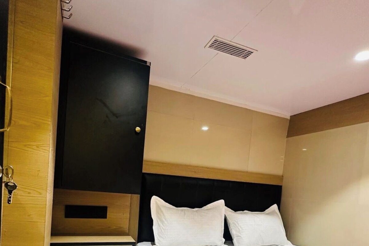 Un dormitorio con cama, televisor montado en la pared y estante empotrado.
