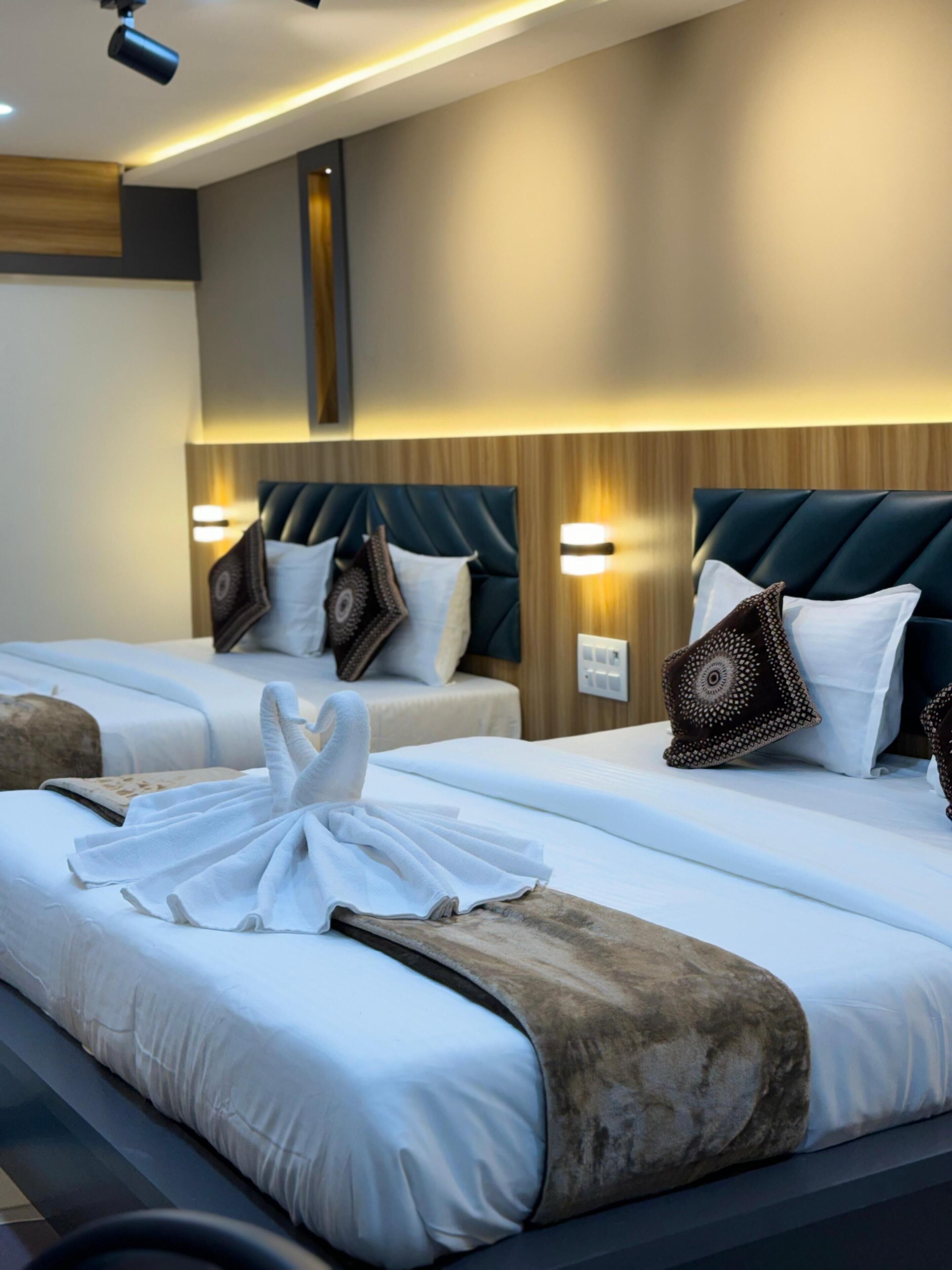 A hotel room with two beds, each with a headboard, bedside lamps, and decorative pillows.