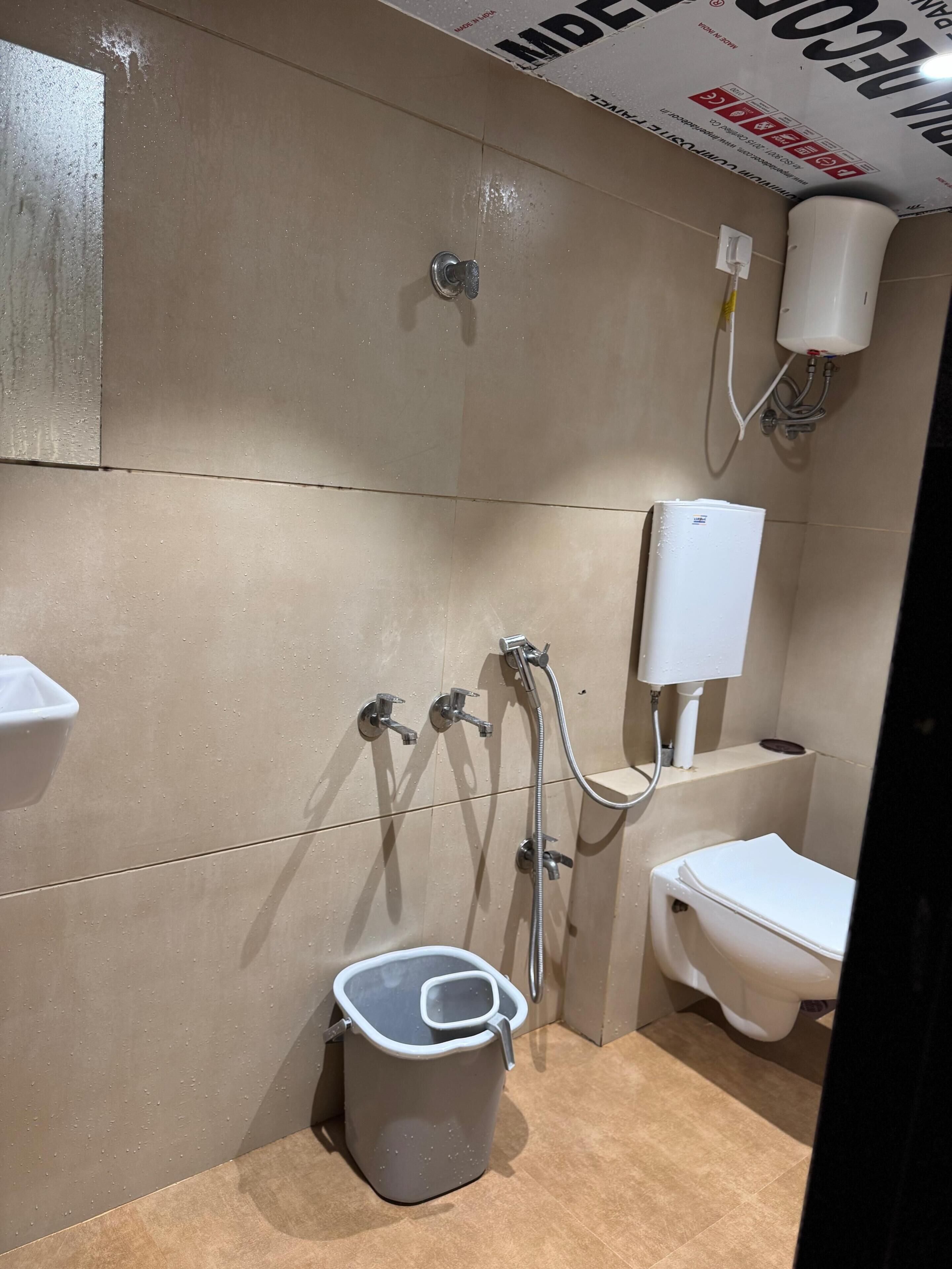 A bathroom with a toilet, a shower, a sink, and a trash bin.