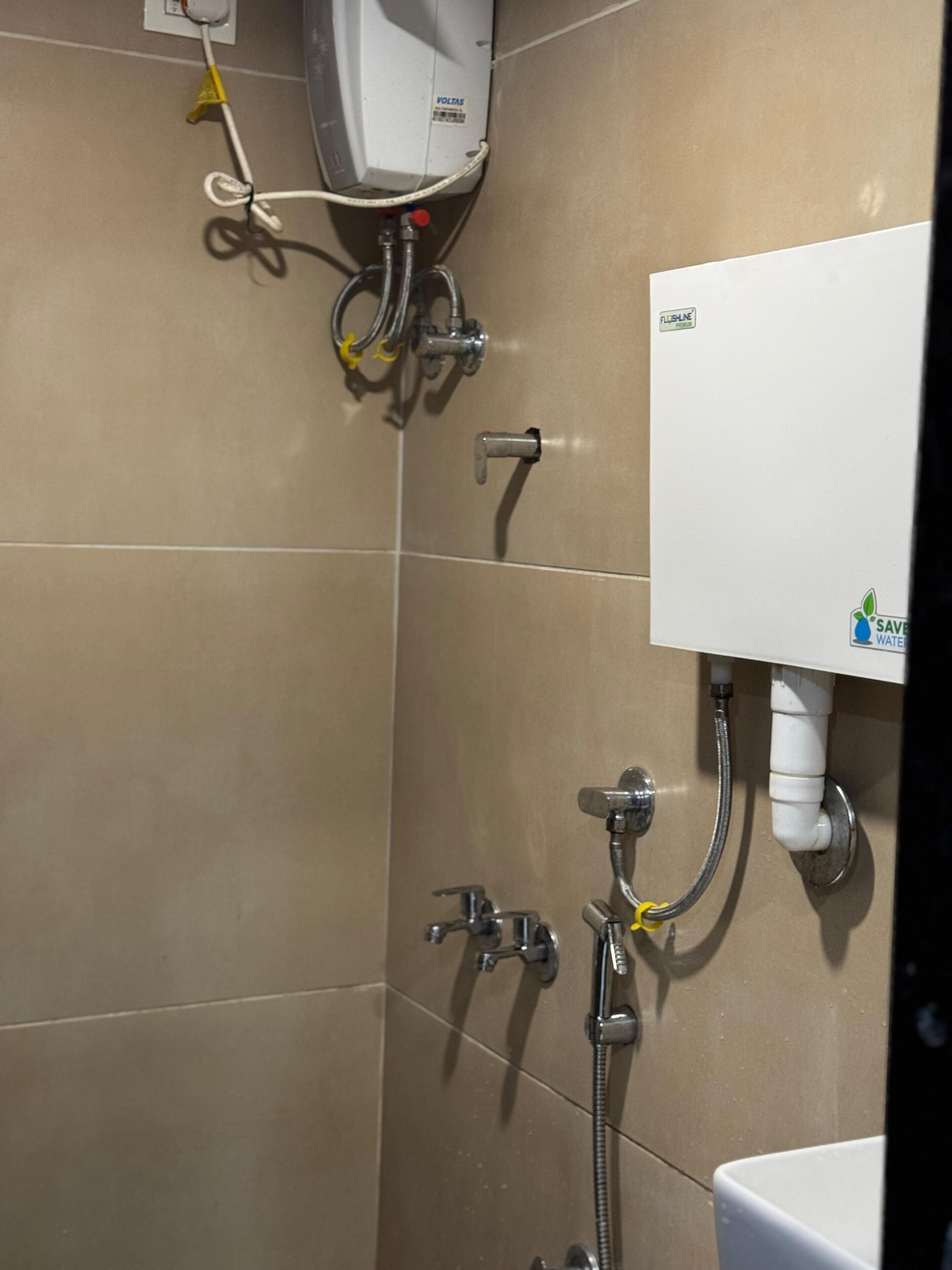 A bathroom with a white toilet, a shower with a handheld showerhead, and a wall-mounted water heater.