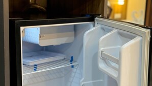 An open refrigerator with shelves and a freezer compartment. - Yatri Stay inn (Mumbai)