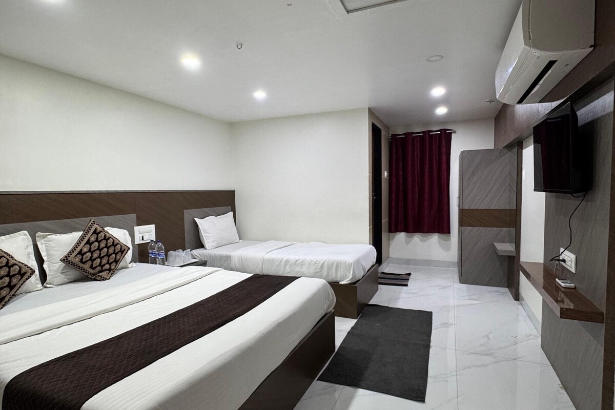 Habitación de hotel con dos camas, televisión, aire acondicionado y baño con ducha.