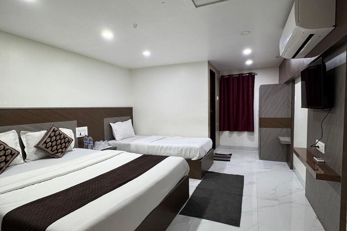 Une chambre d’hôtel avec deux lits, une télévision, la climatisation et une salle de bain avec douche.
