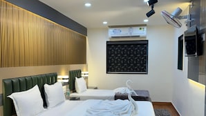 A modern hotel room with a large bed, two bedside tables, a wall-mounted air conditioner, and a ceiling fan. - Yatri Stay inn (Mumbai)